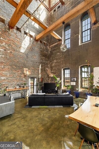 living area with concrete floors, beamed ceiling, and a high ceiling