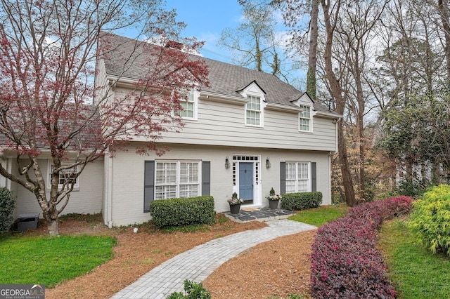 colonial home with brick siding and roof with shingles