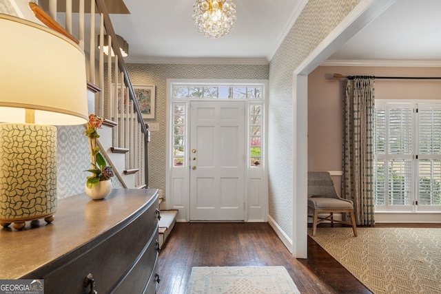 foyer entrance with dark wood-style flooring, ornamental molding, wallpapered walls, and stairs