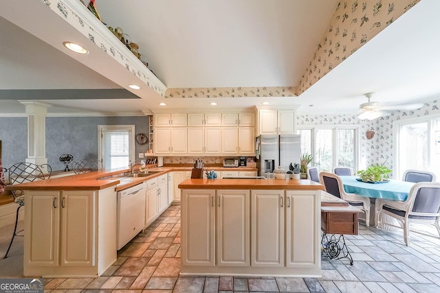 kitchen with butcher block countertops, a breakfast bar area, white dishwasher, and wallpapered walls