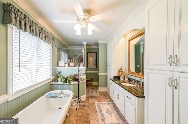 full bath featuring vanity, ceiling fan, a stall shower, a freestanding bath, and ornamental molding
