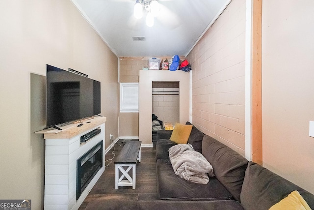 4751 Bill Cheek Rd, Auburn, GA 30011 - living room featuring a ceiling fan, dark wood finished floors, a glass covered fireplace, concrete block wall, and ornamental molding