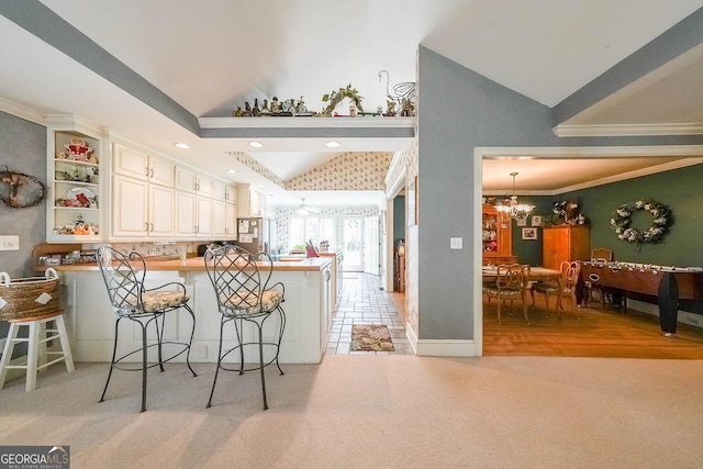 kitchen featuring a breakfast bar area, high vaulted ceiling, a notable chandelier, and a peninsula