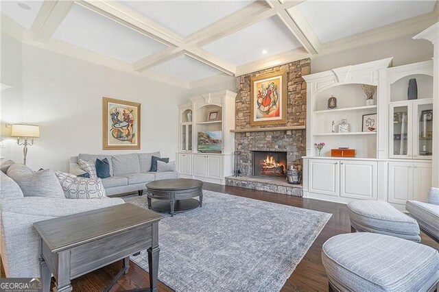 living area featuring a stone fireplace, dark wood finished floors, beam ceiling, ornamental molding, and coffered ceiling