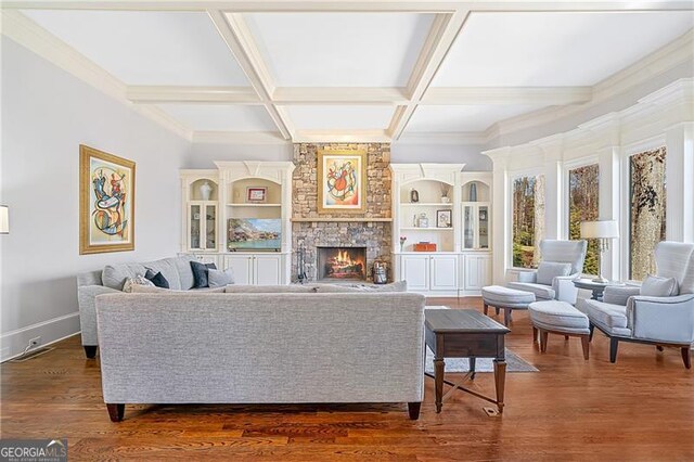 living room with beam ceiling, dark wood finished floors, a stone fireplace, baseboards, and coffered ceiling