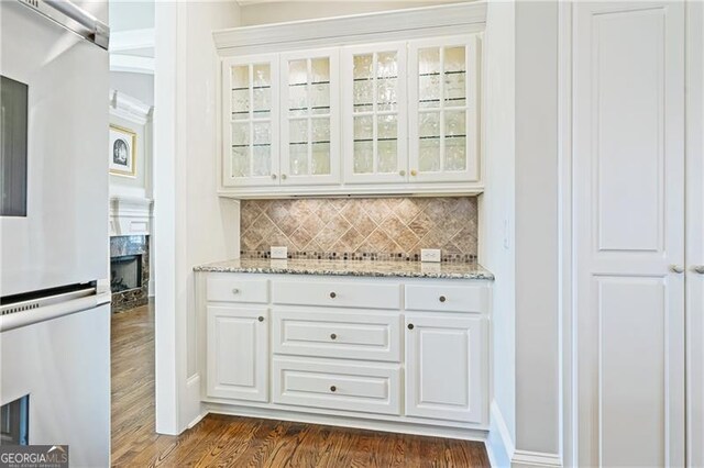 bar featuring decorative backsplash, dark wood-style flooring, a fireplace, and fridge