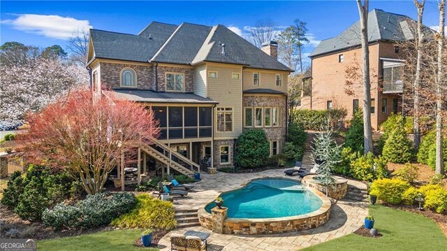 back of house featuring a chimney, an outdoor pool, a sunroom, a patio, and stairs