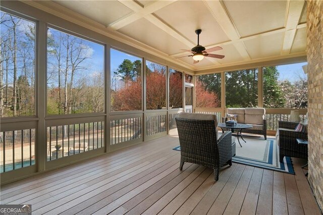 sunroom / solarium featuring coffered ceiling, ceiling fan, outdoor lounge area, and beamed ceiling