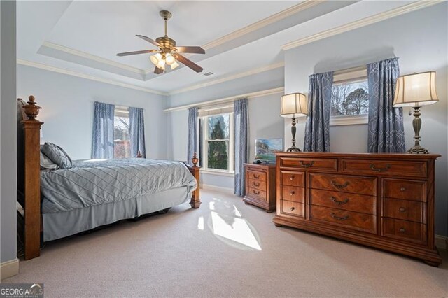 bedroom with a raised ceiling, multiple windows, ornamental molding, and light colored carpet