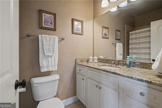 bathroom featuring vanity, baseboards, tile patterned floors, and toilet