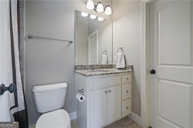 bathroom featuring vanity, baseboards, toilet, and tile patterned flooring