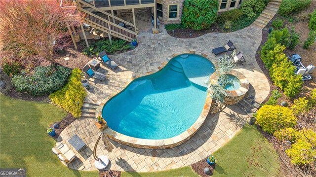 outdoor pool with a patio, a lawn, a wooden deck, and stairway
