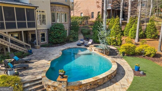 outdoor pool featuring stairway, a lawn, a wooden deck, and a patio area