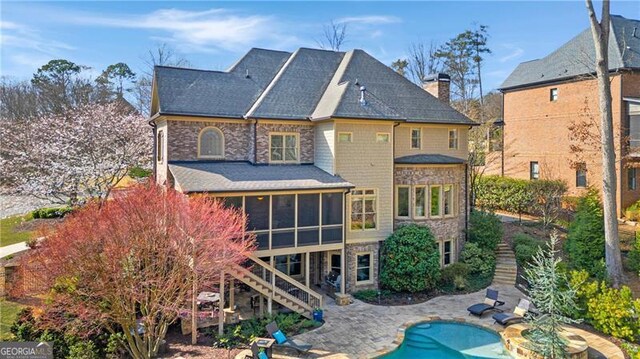 back of house featuring a chimney, an outdoor pool, a sunroom, stairway, and a patio