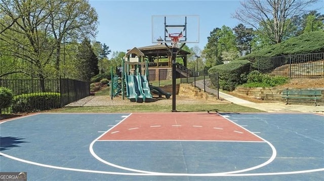 view of basketball court featuring basketball court, fence, and a playground