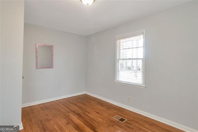 unfurnished room featuring baseboards, wood finished floors, and visible vents