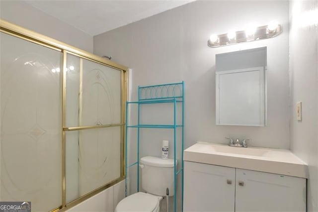 bathroom featuring toilet, vanity, and bath / shower combo with glass door