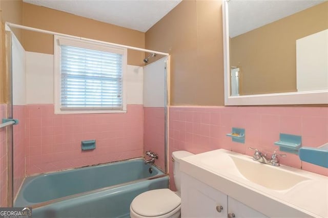 full bathroom with a wainscoted wall, toilet, vanity, tile walls, and shower / tub combination
