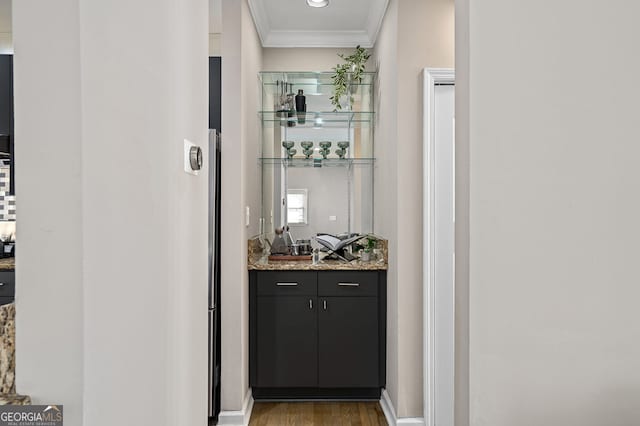 bar with light wood-style flooring, wet bar, and ornamental molding