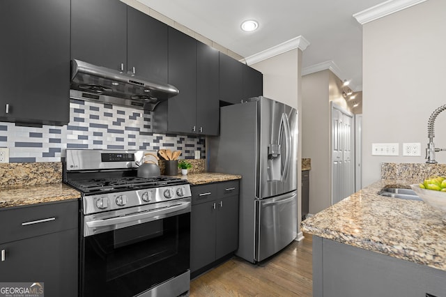 kitchen featuring under cabinet range hood, appliances with stainless steel finishes, crown molding, and a sink