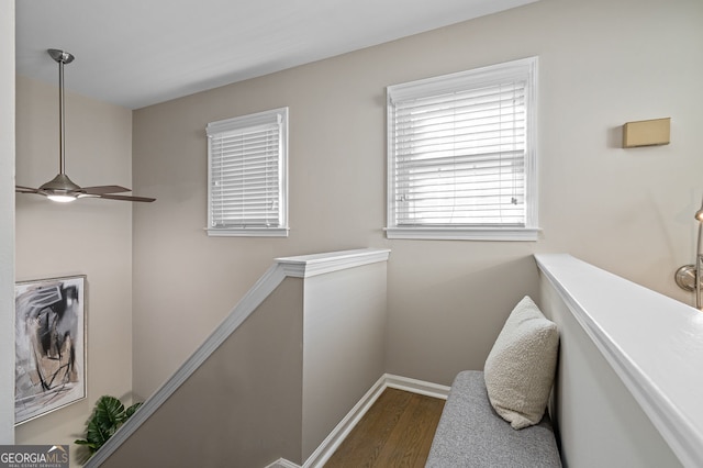 hall featuring baseboards, an upstairs landing, and wood finished floors