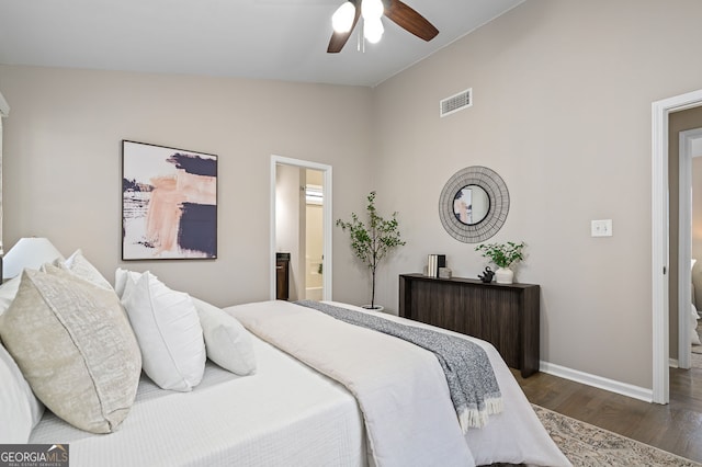 bedroom featuring visible vents, baseboards, vaulted ceiling, wood finished floors, and ensuite bath