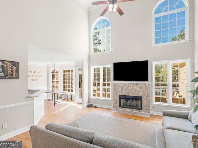 152 Vinings Lake Ct SW, Mableton, GA 30126 - living area featuring crown molding, a tiled fireplace, a ceiling fan, a high ceiling, and light wood-type flooring