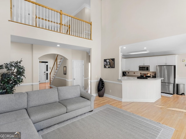 152 Vinings Lake Ct SW, Mableton, GA 30126 - living area featuring stairway, baseboards, a high ceiling, arched walkways, and light wood-style flooring