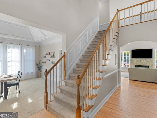 152 Vinings Lake Ct SW, Mableton, GA 30126 - staircase with crown molding, a fireplace, wood finished floors, arched walkways, and a high ceiling