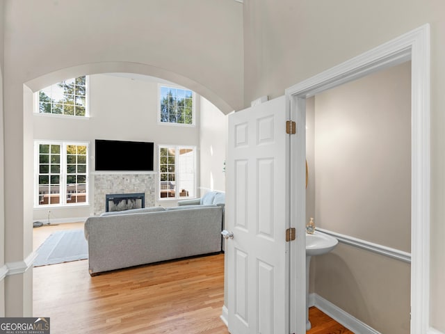 152 Vinings Lake Ct SW, Mableton, GA 30126 - living room featuring baseboards, a high ceiling, arched walkways, light wood-style flooring, and a stone fireplace