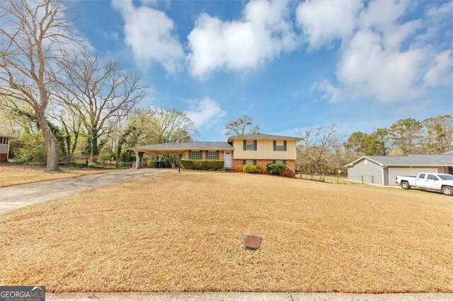 tri-level home with a front yard, concrete driveway, a carport, and fence