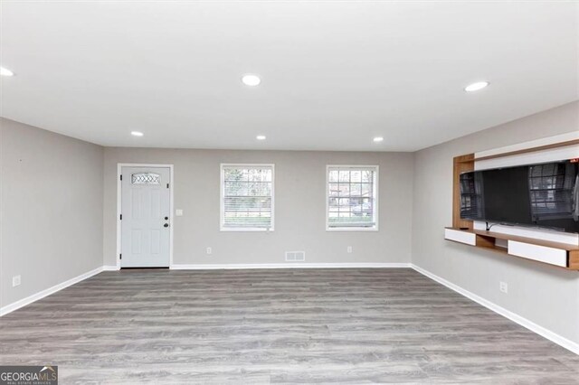 unfurnished living room featuring baseboards, wood finished floors, and recessed lighting