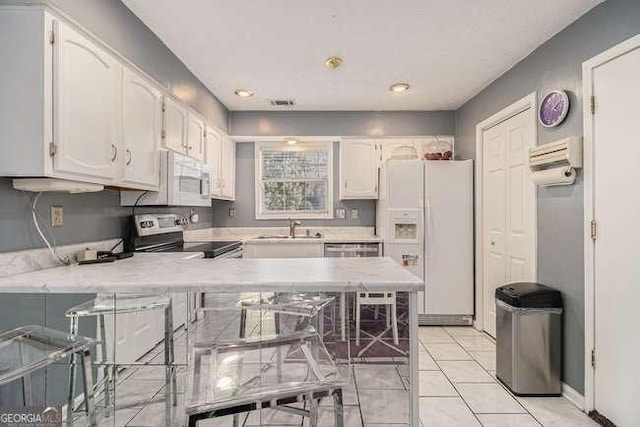 kitchen with white cabinets, a sink, white appliances, light countertops, and a peninsula