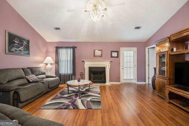 living room with a ceiling fan, visible vents, wood finished floors, and lofted ceiling