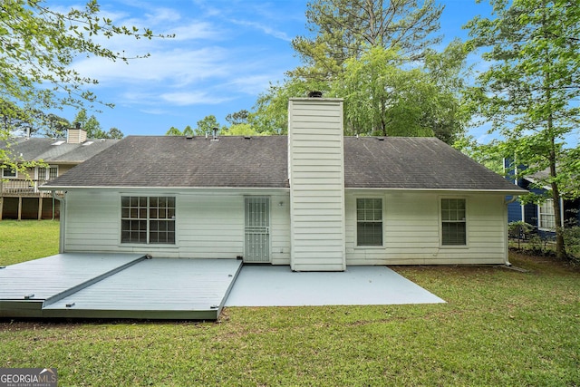 rear view of property featuring a yard, a patio, a chimney, and a shingled roof