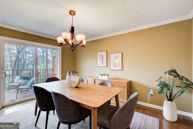 dining space featuring a notable chandelier, light wood-style flooring, baseboards, ornamental molding, and visible vents