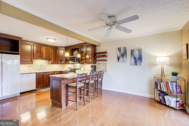 kitchen with a kitchen breakfast bar, a sink, brown cabinetry, stainless steel appliances, and a peninsula