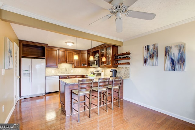 kitchen featuring a kitchen breakfast bar, stainless steel appliances, decorative backsplash, a peninsula, and ceiling fan