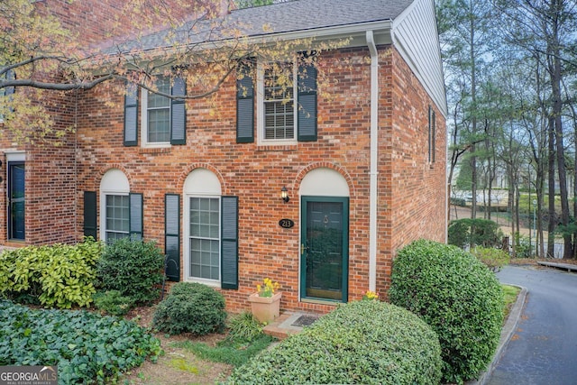colonial house featuring brick siding and a shingled roof