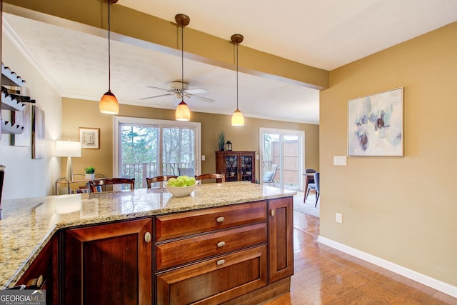 kitchen with light stone countertops, pendant lighting, and ceiling fan