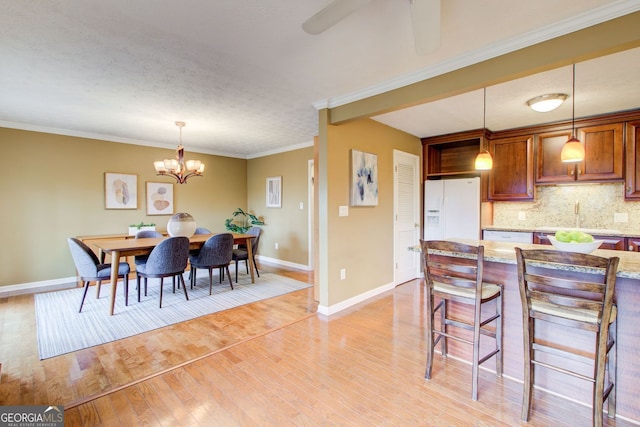 dining room with baseboards, ornamental molding, light wood-style floors, and ceiling fan with notable chandelier
