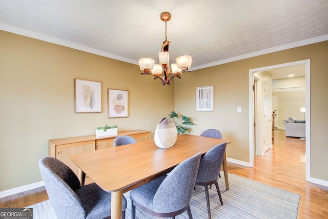 dining space with ornamental molding, baseboards, a notable chandelier, and light wood-type flooring