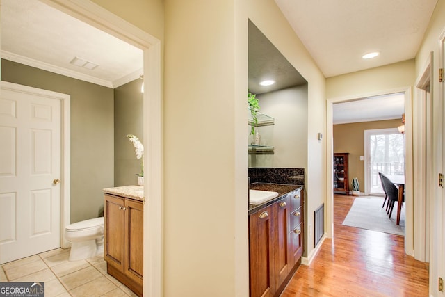 interior space featuring visible vents, light wood finished floors, baseboards, and ornamental molding