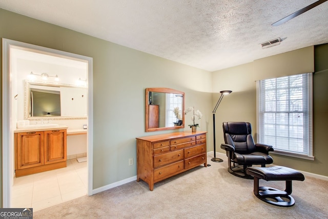 sitting room featuring a textured ceiling, visible vents, baseboards, and light carpet