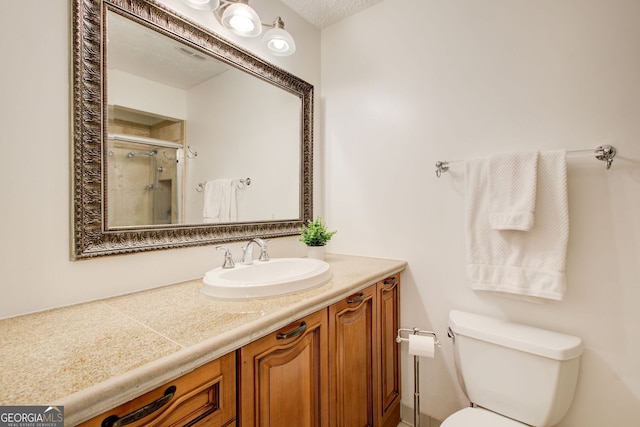 bathroom with vanity, a shower stall, and toilet