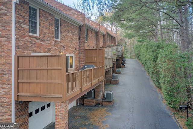 view of home's exterior with brick siding, an attached garage, and central AC unit