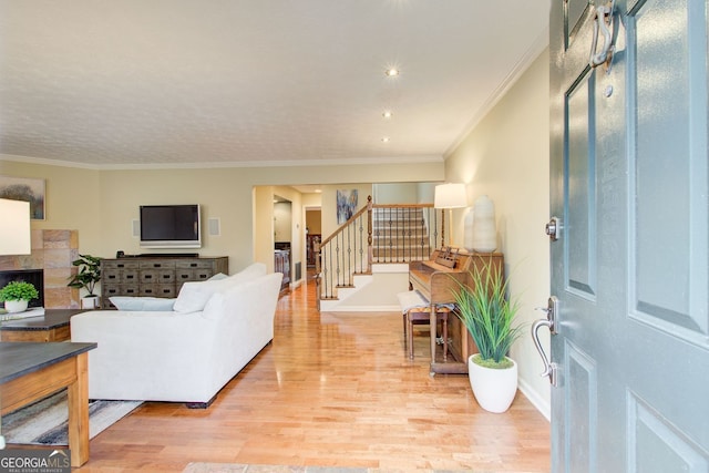 living area with light wood-style flooring, baseboards, stairway, crown molding, and a high end fireplace