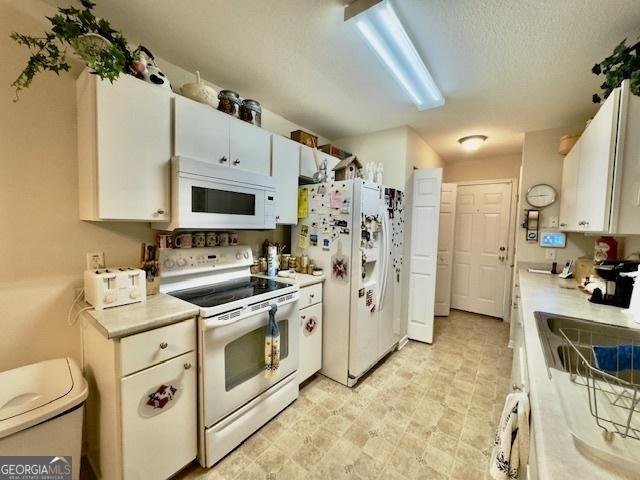5555 Carlton Ln, Garfield, GA 30425 - kitchen featuring white appliances, light countertops, white cabinets, a sink, and washer / clothes dryer