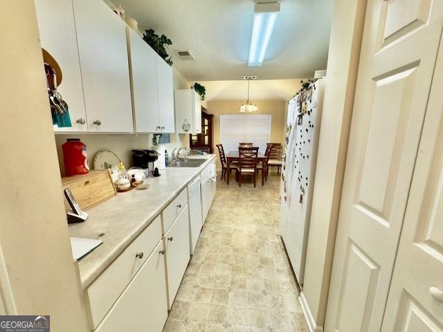 5555 Carlton Ln, Garfield, GA 30425 - kitchen featuring white cabinets, light countertops, white dishwasher, a sink, and hanging light fixtures