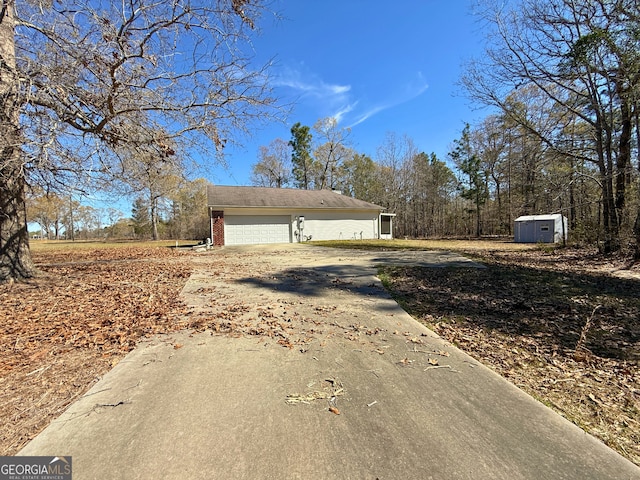 5555 Carlton Ln, Garfield, GA 30425 - view of side of home featuring brick siding, driveway, an outbuilding, a garage, and a shed